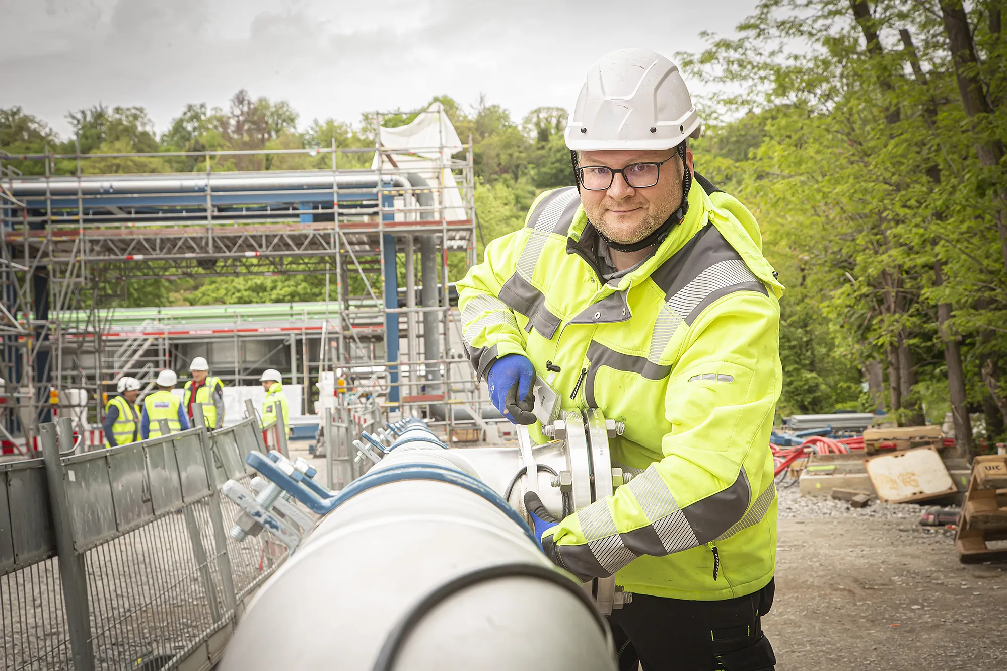 Ein Mann baut auf einer Baustelle an einem breit verlegtem Rohr