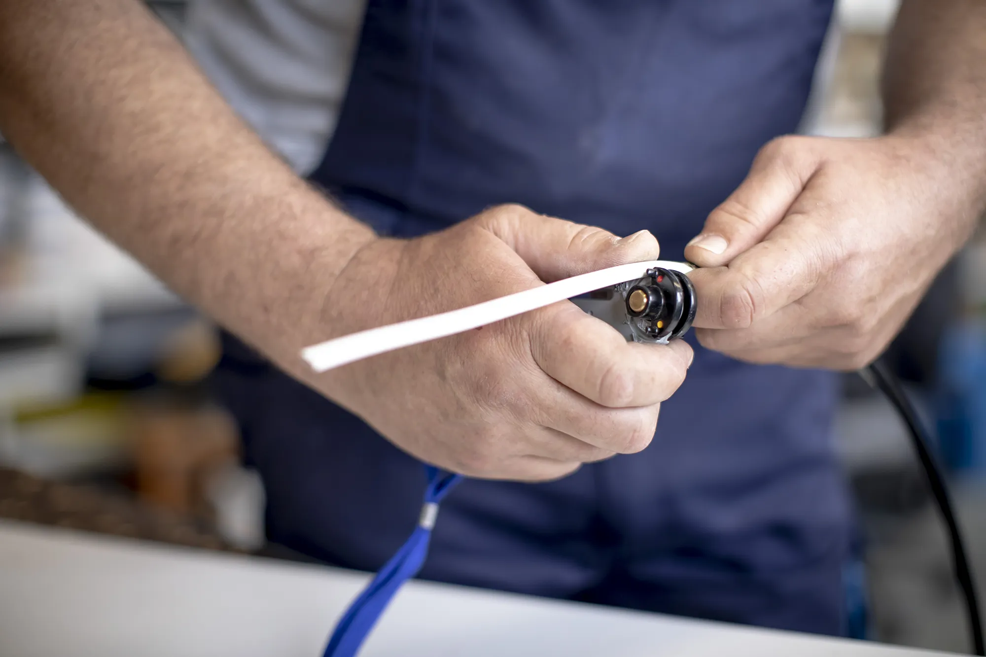 Zwei männliche Hände hantieren an einem Band mit einem weißem Band